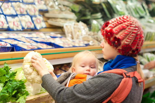 Young mother with toddler girl shopping in supermarket